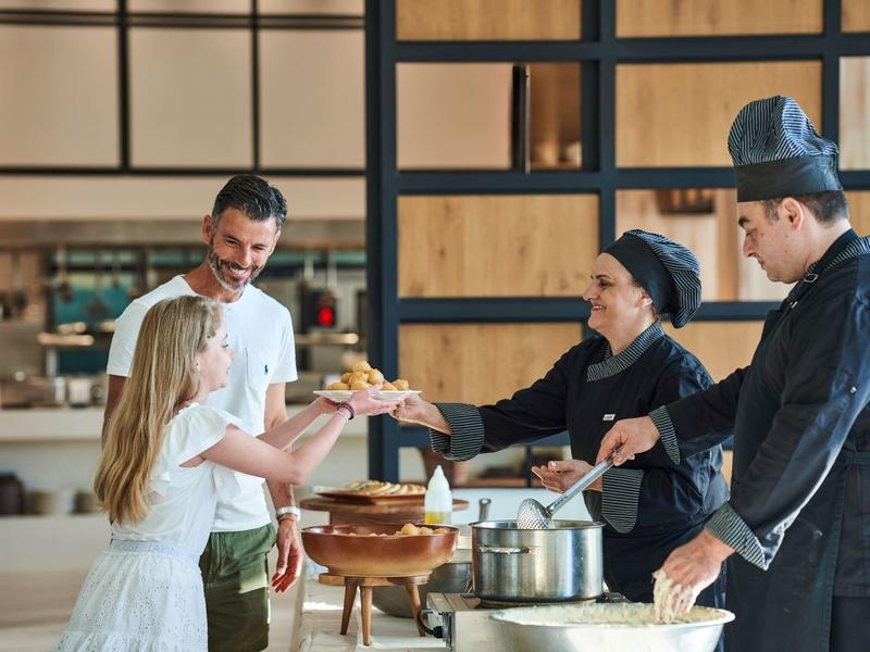 Een meisje krijgt eten geserveerd door koks en een man in een restaurant.
