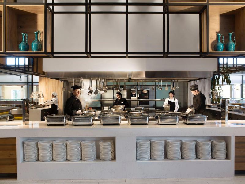 Moderne hotelkeuken met lichte balie en drie koks aan het werk.