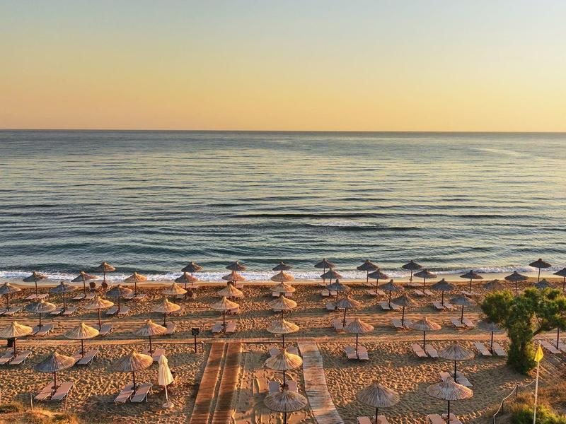 Zonsondergang op het strand met rijen parasols en kalme zee