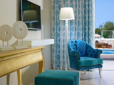 Gezellige blauwe fauteuil met bijpassende voetenbank bij raam met doorschijnende gordijnen en gouden tafel.