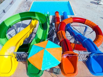 Kleurrijke glijbanen die uitkomen in een helderblauw zwembad op een zonnige dag.