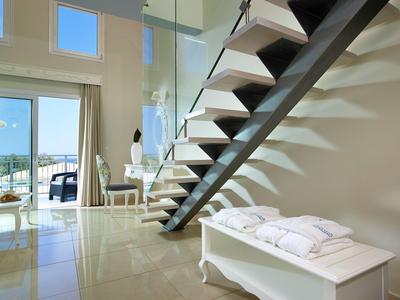 Modern hotelkamer met zwevende trap, grote ramen en gezellige zithoek.