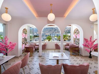 Elegante eetruimte met roze stoelen, bogen en stadszicht door grote ramen.