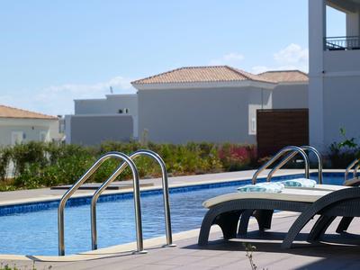 Moderne zwembad met ligstoelen in een hotel tuin op een zonnige dag.