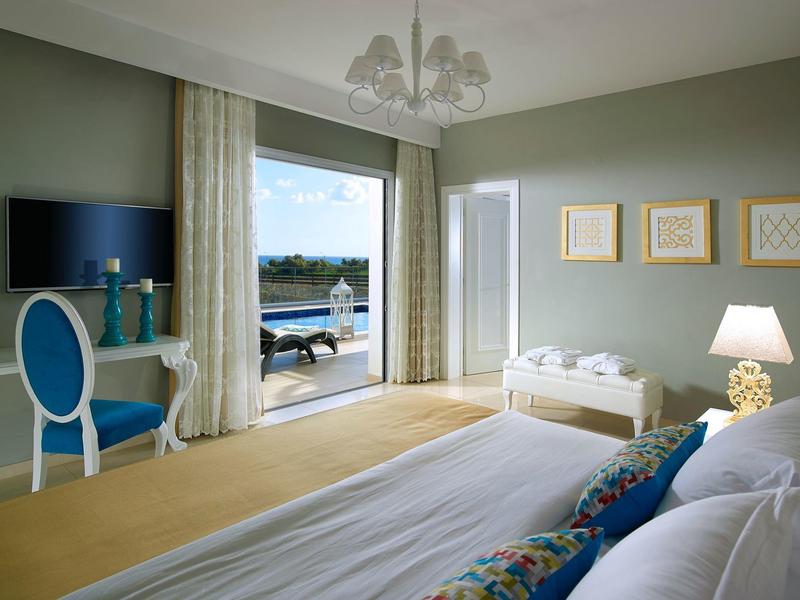 Lichte hotelkamer met tweepersoonsbed, balkon en uitzicht op het zwembad.