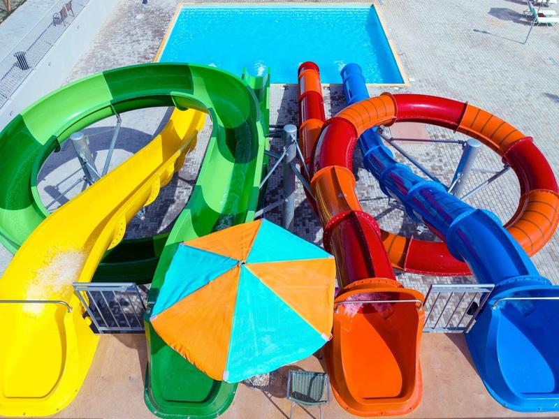 Kleurrijke glijbanen die uitkomen in een helderblauw zwembad op een zonnige dag.