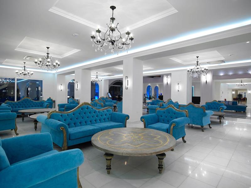 Luxe lounge met blauwe fluwelen banken en ronde tafels onder elegante kroonluchters.