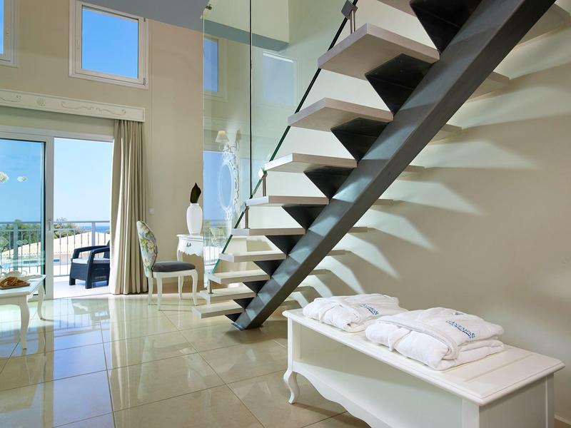 Modern hotelkamer met zwevende trap, grote ramen en gezellige zithoek.