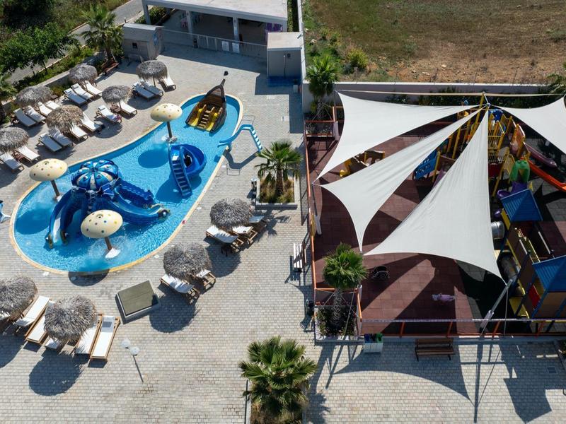 Buitenzwembad met ligstoelen en schaduwrijke zitplaatsen onder witte zeilen.