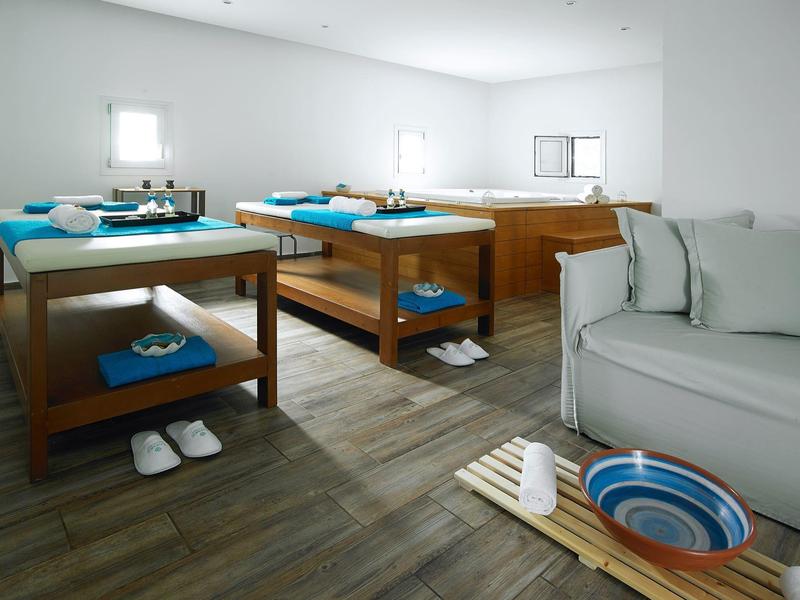 Lichte spa ontspanningsruimte met massagetafels, witte handdoeken en rustige sfeer.