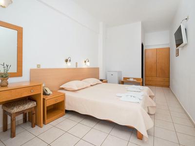 Helles, schlicht eingerichtetes Schlafzimmer mit zwei Betten, kleinem Schreibtisch und Fernseher an der Wand.
