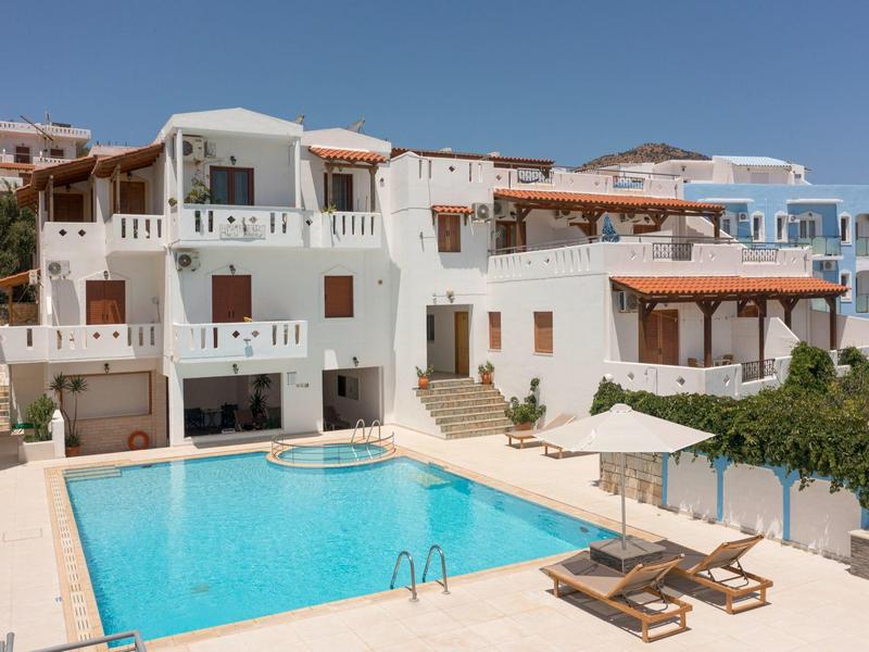 Hotel con piscina al aire libre rodeada de tumbonas y sombrillas en día soleado