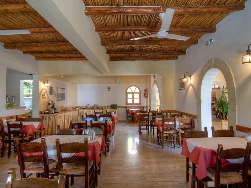 Comedor luminoso con muebles de madera y techo de vigas en un hotel.