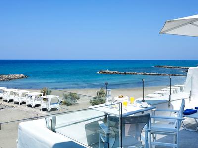 Zwei weiße Strandbetten mit Vorhängen am Sandstrand bei Sonnenuntergang am Meer.