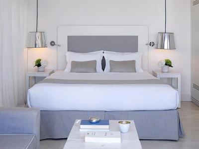 Modern, bright hotel room with large bed, gray accents, and stylish lamps.