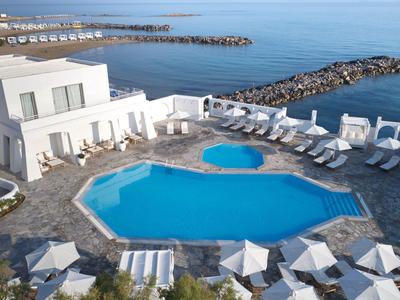 Área moderna de piscina con tumbonas y vista al mar en un complejo hotelero.