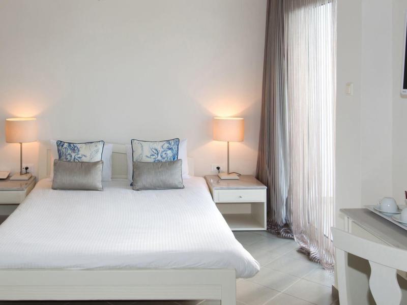 Modernes Hotelzimmer mit Doppelbett, Nachttischen und Schreibtisch mit TV an der Wand.