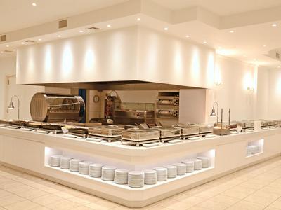 Cucina d'hotel moderna e minimalista con superfici bianche e illuminazione integrata.