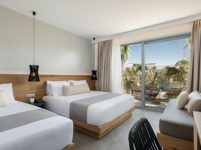 Camera d'hotel moderna con due letti, balcone e vista sulle palme.