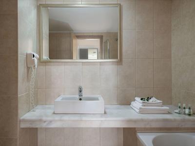 Specchio bagno moderno e luminoso dell'hotel con lavabo rettangolare e asciugamani bianchi.