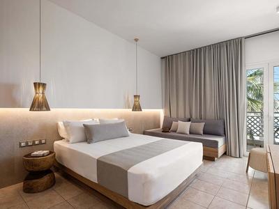 Camera d'albergo moderna con letto grande, divano, tende e accesso a balcone o terrazza.