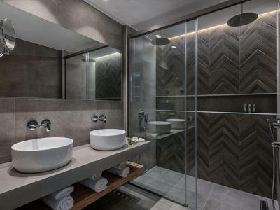 Bagno moderno con due lavandini, grande specchio e doccia con parete in vetro.