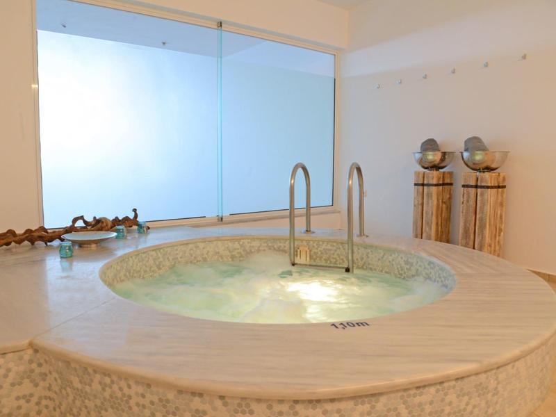 Vasca idromassaggio moderna con cascate e grandi finestre in una stanza luminosa.