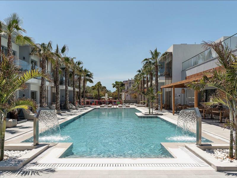 Piscina moderna dell'hotel con palme e sdraio sotto un cielo azzurro.