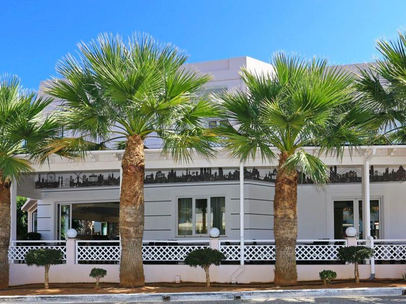 Edificio moderno di hotel o ristorante con palme e terrazza al sole.