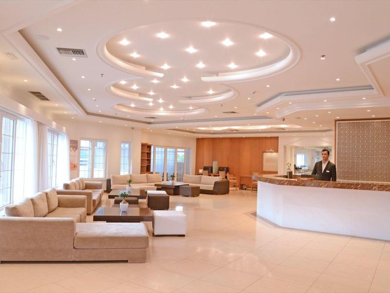 Luminosa hall dell'hotel con aree salotto, illuminazione moderna a soffitto e reception.