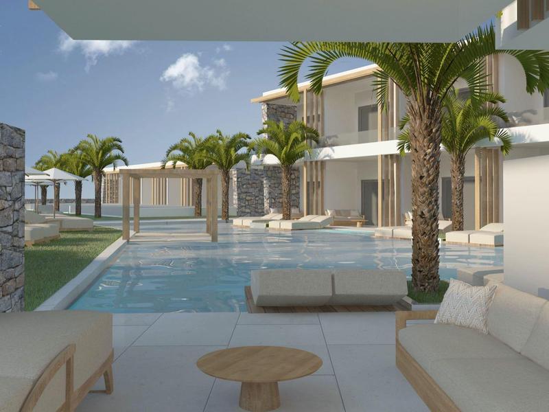 Area piscina moderna dell'hotel con lettini, tavoli e palme sotto un cielo limpido.