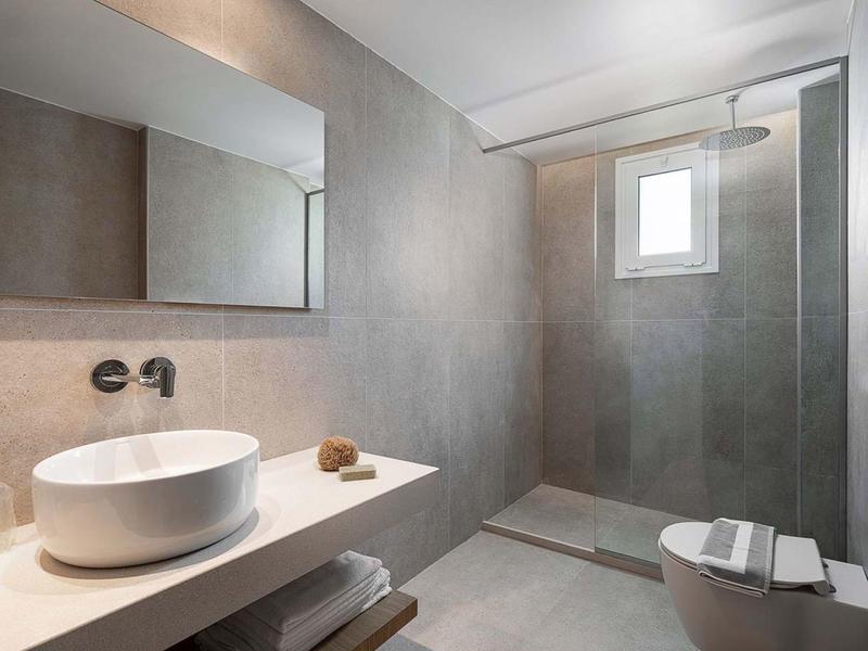 Bagno moderno con lavabo rotondo, grande parete specchiata e doccia walk-in.