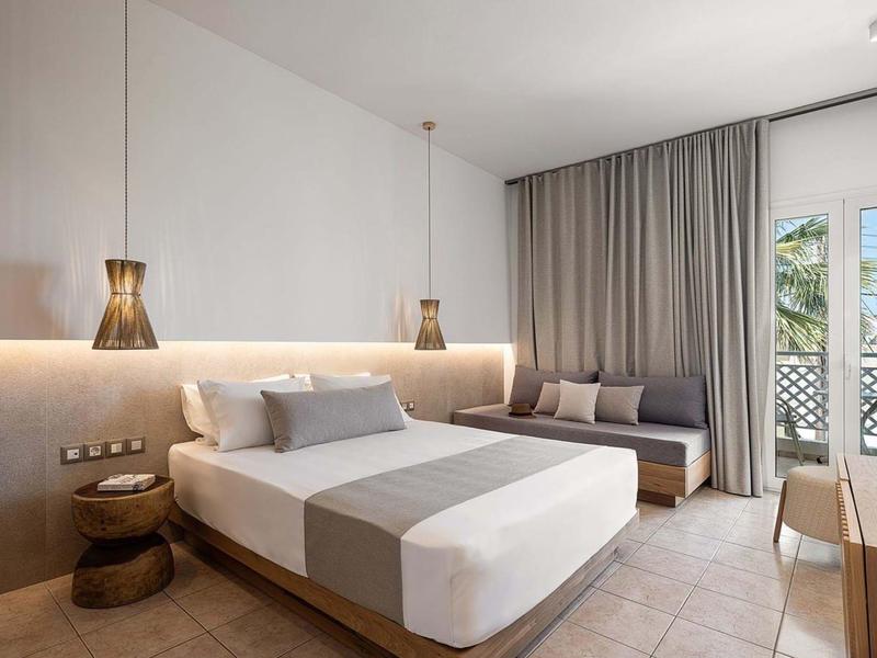 Camera d'albergo moderna con letto grande, divano, tende e accesso a balcone o terrazza.