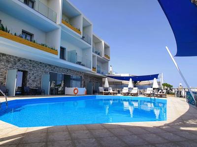 Hotel moderno con piscina all'aperto e area salotto sotto una vela parasole blu