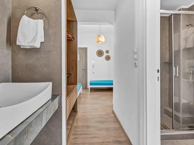 Moderner Hotelflur mit Badewanne, Dusche und farbigen Sitzbänken am Ende.