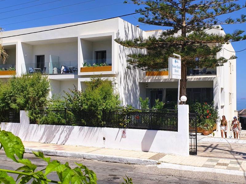 Modernes zweistöckiges weißes Haus mit Balkonen und grünen Sträuchern im sonnigen Garten.