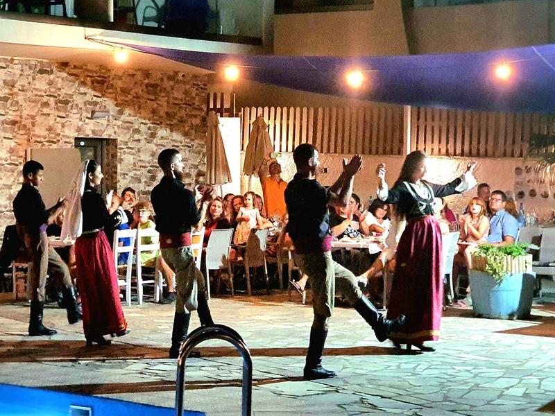 Tanzgruppe lebt traditionelle Kultur mit festlicher Beleuchtung und Publikum im Hintergrund.