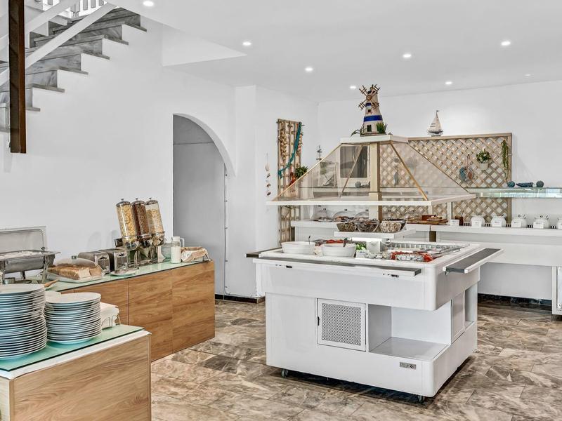 Modern eingerichtete Selbstbedienungs-Küche mit weißen Möbeln und Holzdetails.