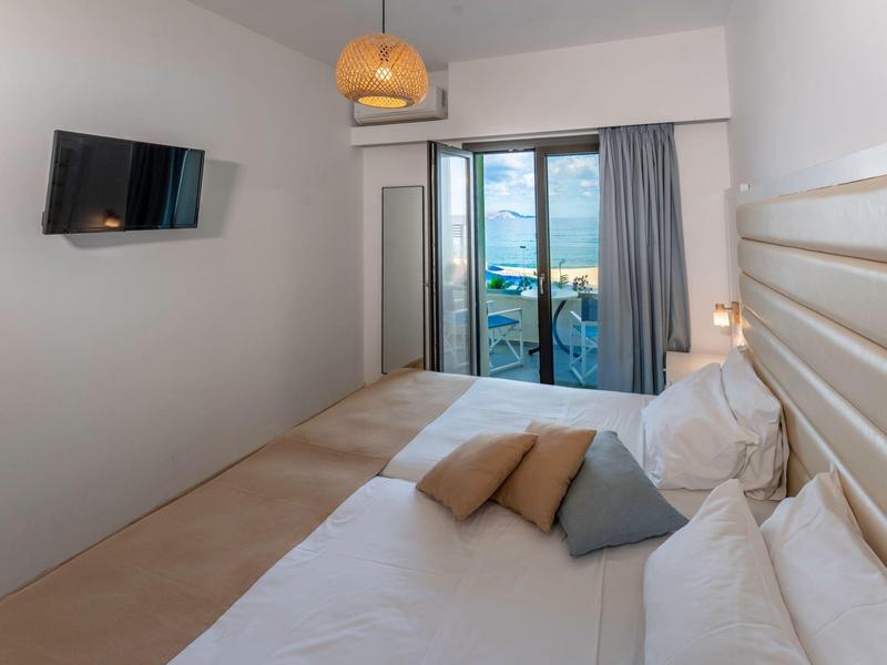 Modernes Hotelzimmer mit Doppelbett, Fernseher und Balkon mit Meerblick.