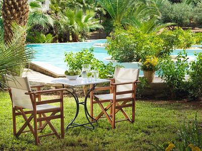 Gemütlicher Außenbereich mit Tisch und Stühlen neben einem Pool in einem grünen Garten.