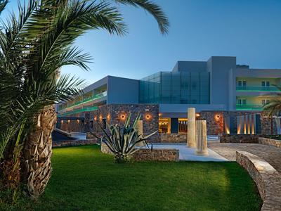 Moderner Hotelkomplex mit beleuchtetem Pool und Palmen bei klarem Himmel.