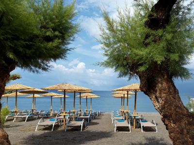 Plaża z leżakami i słomianymi parasolami nad spokojnym morzem pod niebieskim niebem.