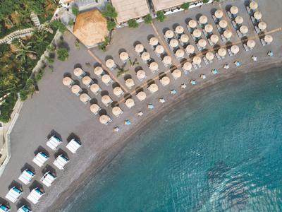 Widok z lotu ptaka na plażę z parasolami, leżakami i turkusową wodą.