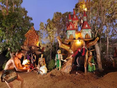 Wieczorna scena grupy w tradycyjnych strojach przed oświetlonym, ozdobnym świątynią.