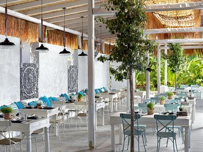 Helles, modernes Restaurant mit weißen Möbeln und grünen Pflanzen im Innenbereich.