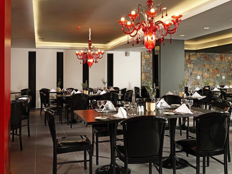 Elegancka restauracja z czarnymi krzesłami, drewnianymi stołami i czerwonymi żyrandolami.