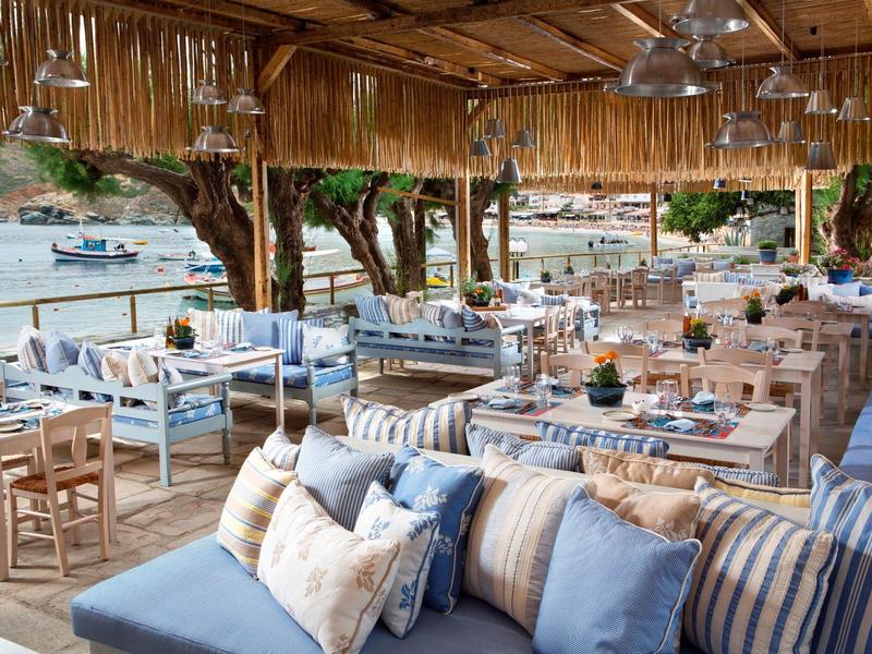 Otwarty pawilon plażowy z wygodnymi miejscami do siedzenia i widokiem na morze.