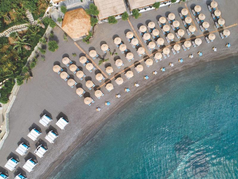 Widok z lotu ptaka na plażę z parasolami, leżakami i turkusową wodą.