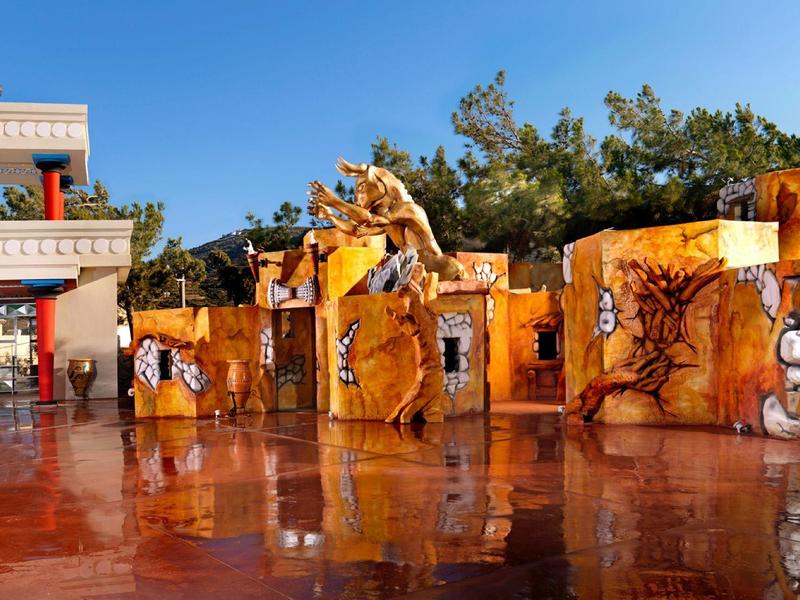 Kolorowe malowidła na ścianie na słonecznym, otwartym terenie z czerwonym kamiennym podłożem i niebieskim niebem.