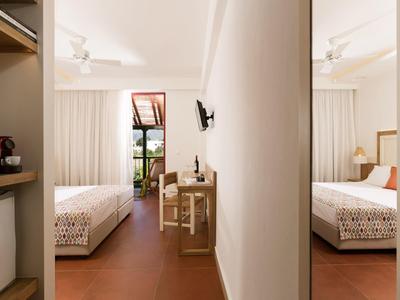 Camera d'hotel con letti singoli, mobili semplici e balcone.